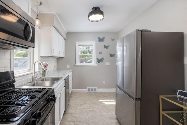 2801 Harvey St, La Crosse, WI 54603 - kitchen featuring stainless steel appliances, a sink, light countertops, white cabinets, and decorative backsplash