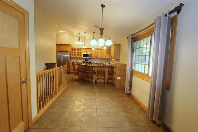 1808 Curtiss St, Eau Claire, WI 54703 - kitchen with stainless steel appliances, vaulted ceiling, a chandelier, a breakfast bar, and glass insert cabinets