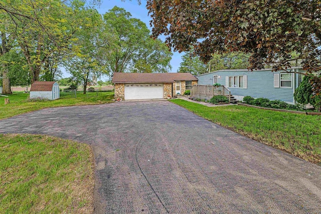 N10678 US Highway 151, Malone, WI 53049 - view of front of house featuring asphalt driveway, stone siding, a front yard, a garage, and a deck
