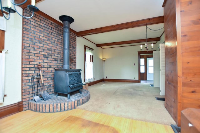 735 Oakwood St, Wild Rose, WI 54984 - unfurnished living room with a wood stove, wood finished floors, beamed ceiling, baseboards, and brick wall