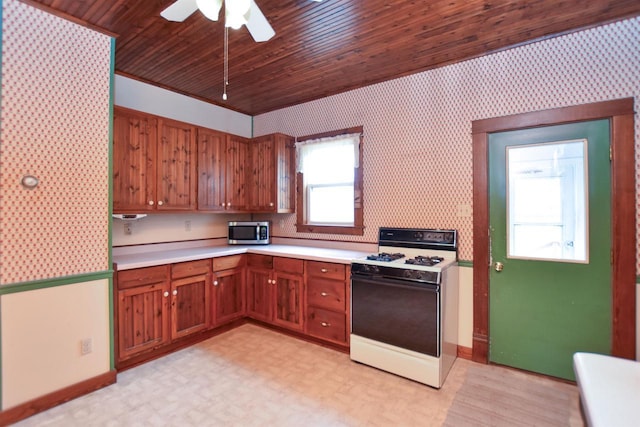 735 Oakwood St, Wild Rose, WI 54984 - kitchen with white range with gas cooktop, stainless steel microwave, light countertops, a ceiling fan, and brown cabinetry