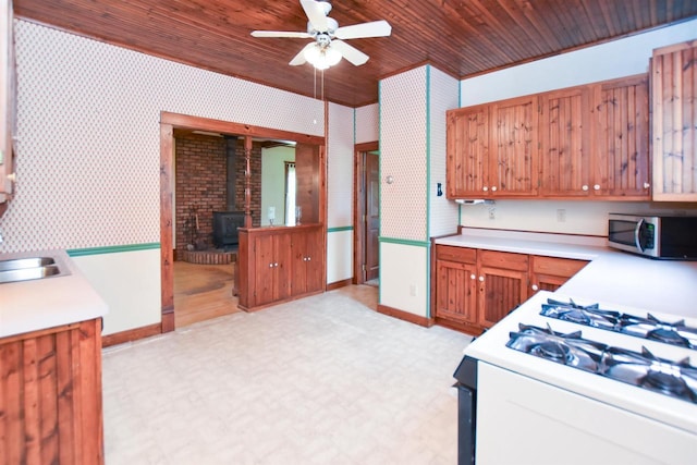 735 Oakwood St, Wild Rose, WI 54984 - kitchen with stainless steel microwave, white gas stove, a wood stove, a ceiling fan, and light flooring
