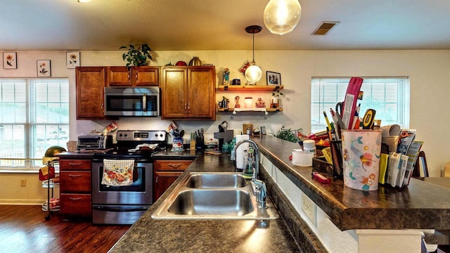 619 Reena Ave Unit 8, Fort Atkinson, WI 53538 - kitchen featuring appliances with stainless steel finishes, a sink, dark countertops, dark wood-style floors, and hanging light fixtures