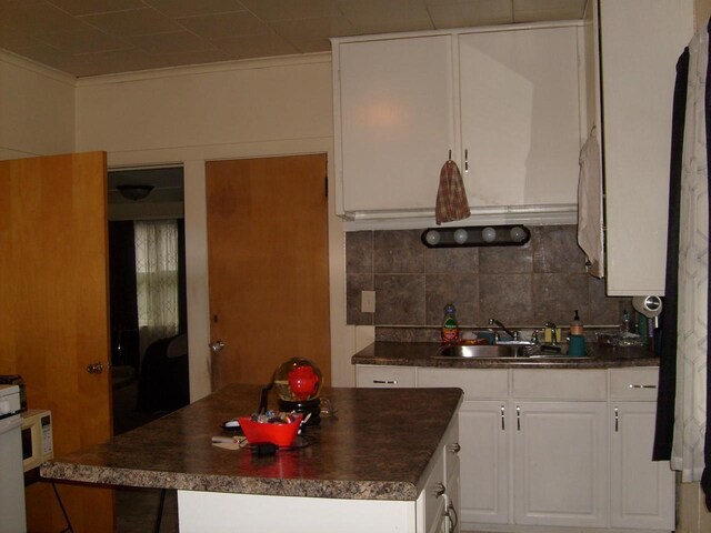 1330 Ceape Ave, Oshkosh, WI 54901 - kitchen featuring a sink, dark countertops, a center island, decorative backsplash, and crown molding