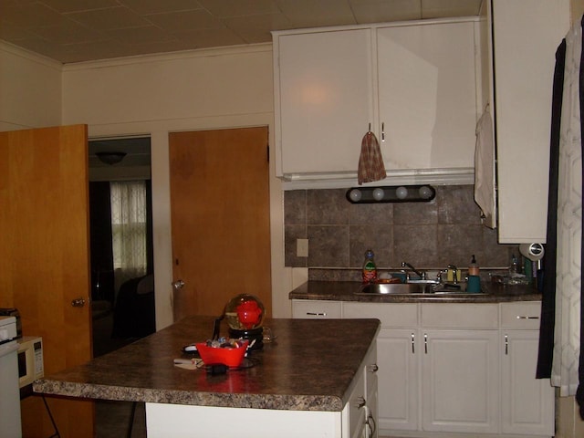 1330 Ceape Ave, Oshkosh, WI 54901 - kitchen featuring a sink, dark countertops, a kitchen island, tasteful backsplash, and crown molding