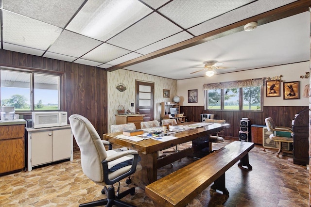 N1815 County Road T, Brodhead, WI 53520 - dining space featuring wooden walls, light stone finish flooring, a wainscoted wall, and a ceiling fan