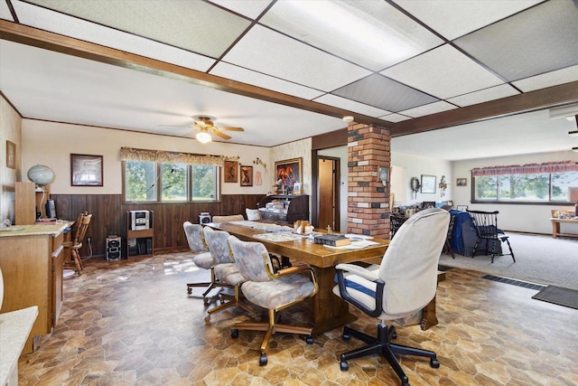 N1815 County Road T, Brodhead, WI 53520 - dining space with stone flooring, a wainscoted wall, wooden walls, a drop ceiling, and ceiling fan