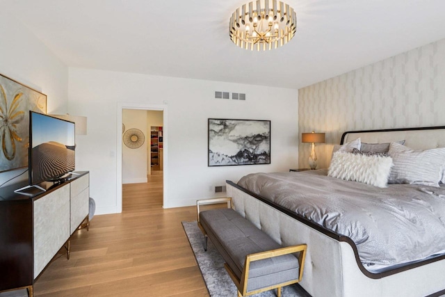 7678 Badger Run Ct, Verona, WI 53593 - bedroom featuring wallpapered walls, a chandelier, wood finished floors, and baseboards