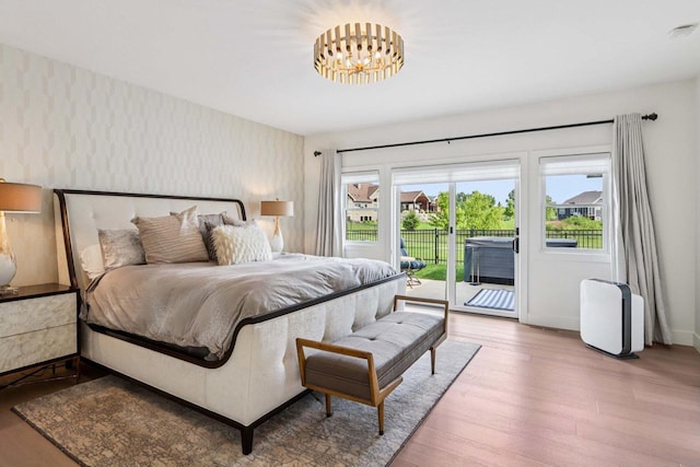 7678 Badger Run Ct, Verona, WI 53593 - bedroom featuring access to exterior, wood finished floors, baseboards, wallpapered walls, and a chandelier