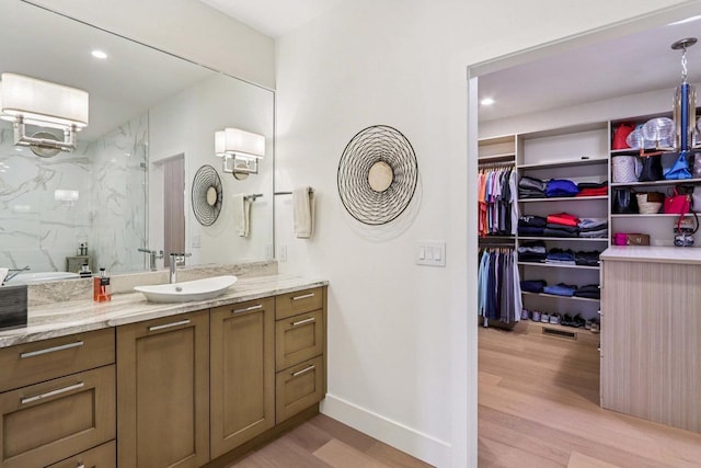 7678 Badger Run Ct, Verona, WI 53593 - full bath with vanity, wood finished floors, a marble finish shower, a walk in closet, and recessed lighting