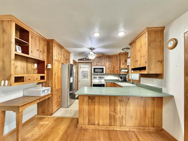 3117 Canterbury Ln, Janesville, WI 53546 - kitchen featuring appliances with stainless steel finishes, a sink, light wood-style floors, a peninsula, and decorative backsplash