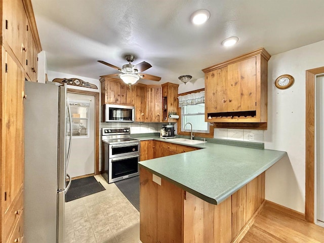 3117 Canterbury Ln, Janesville, WI 53546 - kitchen with stainless steel appliances, a peninsula, a sink, ceiling fan, and backsplash