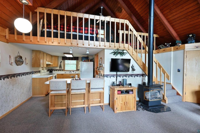 2775 Lake Rd, Barnes, WI 54873 - carpeted living area featuring a wood stove, wood ceiling with exposed beams, stairs, a sink, and high vaulted ceiling
