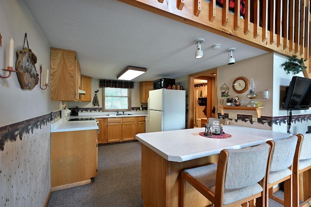 2775 Lake Rd, Barnes, WI 54873 - kitchen with white appliances, a sink, light countertops, dark carpet, and a breakfast bar area