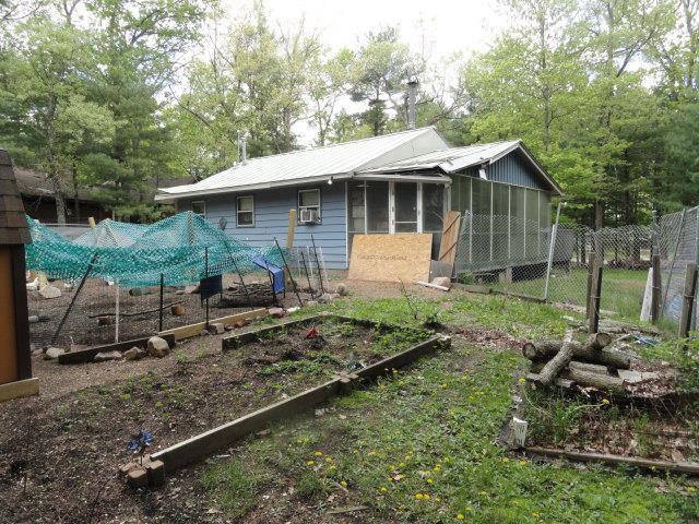 W4643 S Pearl Lake Rd, Redgranite, WI 54970 - rear view of property featuring a vegetable garden, a sunroom, and metal roof