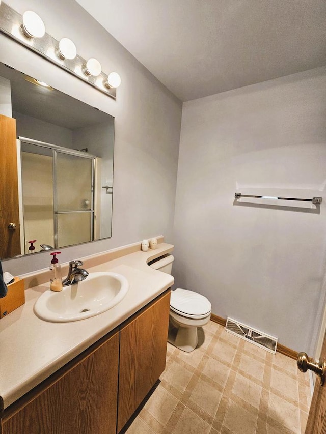 1114 W St, Racine, WI 53404 - bathroom featuring vanity, a shower stall, toilet, tile patterned floors, and baseboards