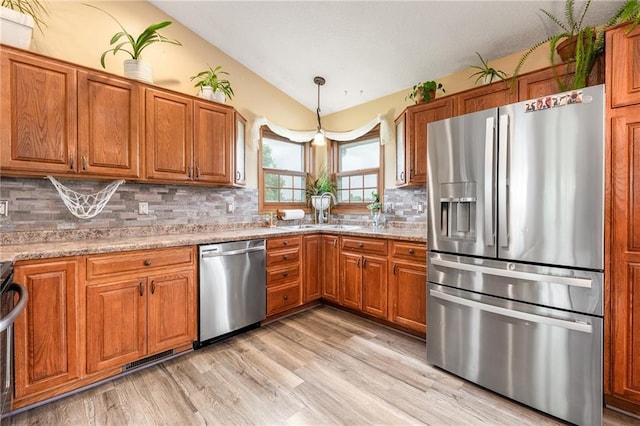 4868 183rd St, Chippewa Falls, WI 54729 - kitchen with appliances with stainless steel finishes, a sink, brown cabinets, vaulted ceiling, and light wood-style flooring