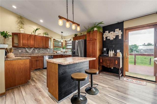 4868 183rd St, Chippewa Falls, WI 54729 - kitchen featuring appliances with stainless steel finishes, light wood-type flooring, lofted ceiling, brown cabinetry, and backsplash