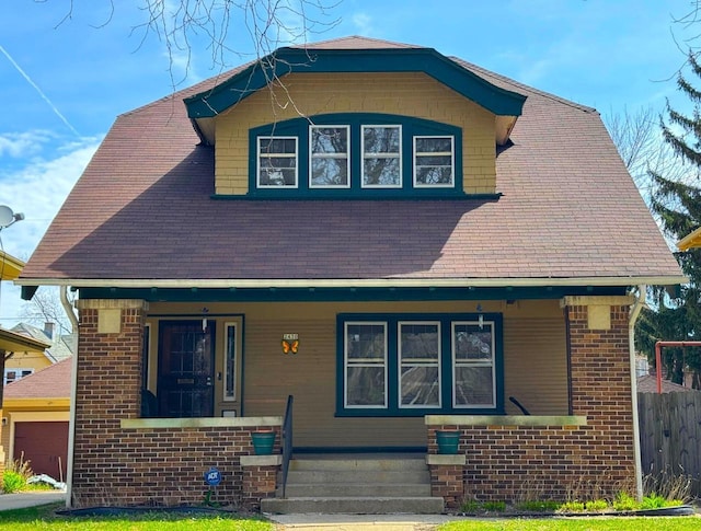 2430 N Grant Blvd, Milwaukee, WI 53210 - view of front of home with covered porch, roof with shingles, brick siding, and a garage