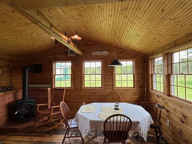 12258 Mosquito Brook Rd, Hayward, WI 54843 - dining area with wood-type flooring, vaulted ceiling, a wood stove, plenty of natural light, and wood walls