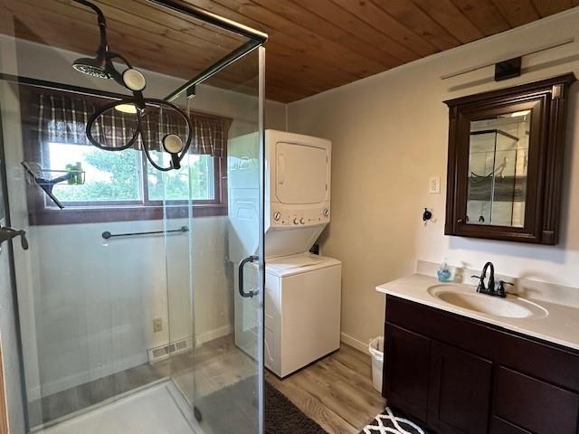 12258 Mosquito Brook Rd, Hayward, WI 54843 - laundry room featuring stacked washer / dryer, wood ceiling, and light wood-style floors