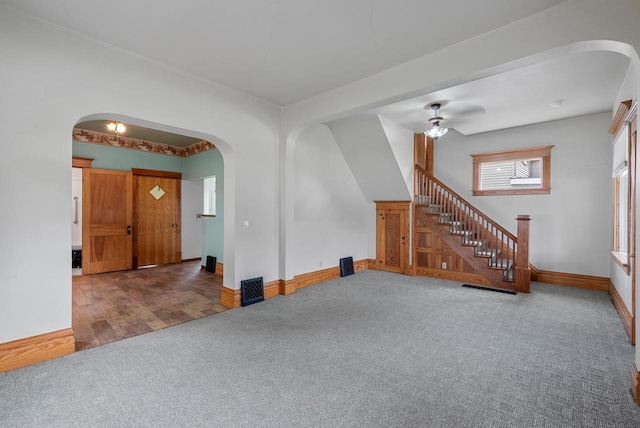 210 Gilmore Ave, Beaver Dam, WI 53916 - unfurnished living room with arched walkways, carpet flooring, stairway, baseboards, and ceiling fan