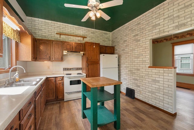 210 Gilmore Ave, Beaver Dam, WI 53916 - kitchen featuring white appliances, a sink, under cabinet range hood, brick wall, and dark wood-type flooring