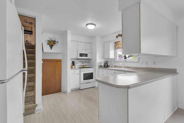 2117 N 27th St, Sheboygan, WI 53081 - kitchen with white appliances, a sink, white cabinetry, light countertops, and a peninsula