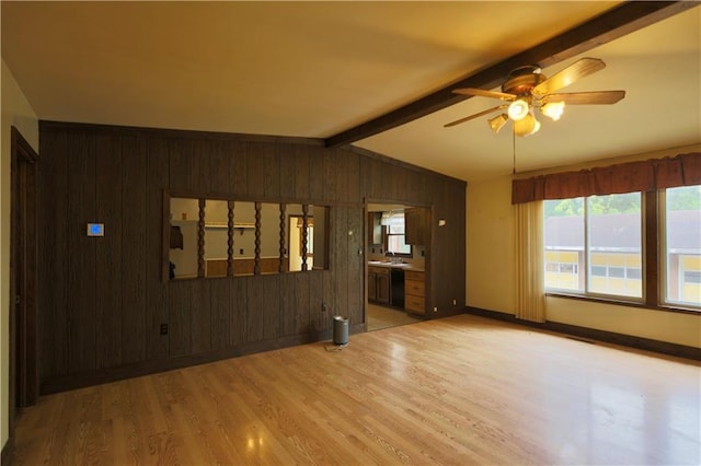 1217 Andover Ave, Eau Claire, WI 54703 - unfurnished living room featuring wooden walls, light wood finished floors, a ceiling fan, plenty of natural light, and baseboards