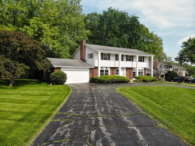 6538 N Bethmaur Ln, Glendale, WI 53209 - view of front of house with asphalt driveway, an attached garage, brick siding, a chimney, and a front yard