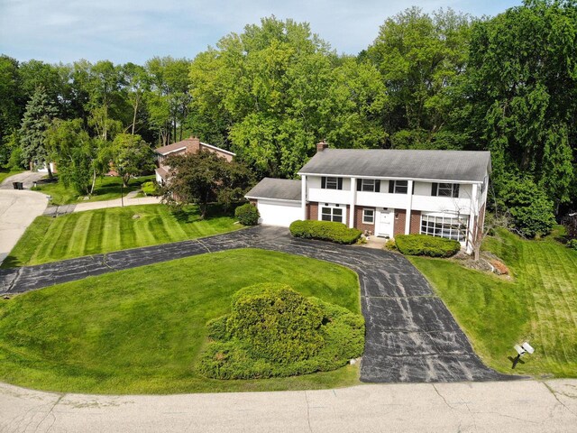 6538 N Bethmaur Ln, Glendale, WI 53209 - view of front of house with a chimney, brick siding, a front lawn, and a detached garage
