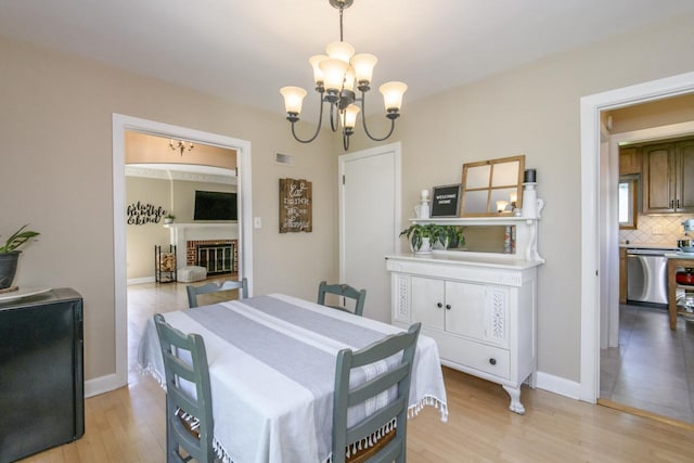 5744 W Rita Dr, West Allis, WI 53219 - dining space with a chandelier, light wood-style floors, baseboards, and a fireplace