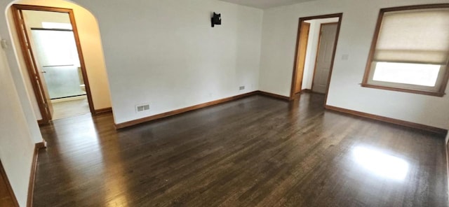 2210 Taylor Ave, Racine, WI 53403 - empty room featuring arched walkways, dark wood finished floors, and baseboards