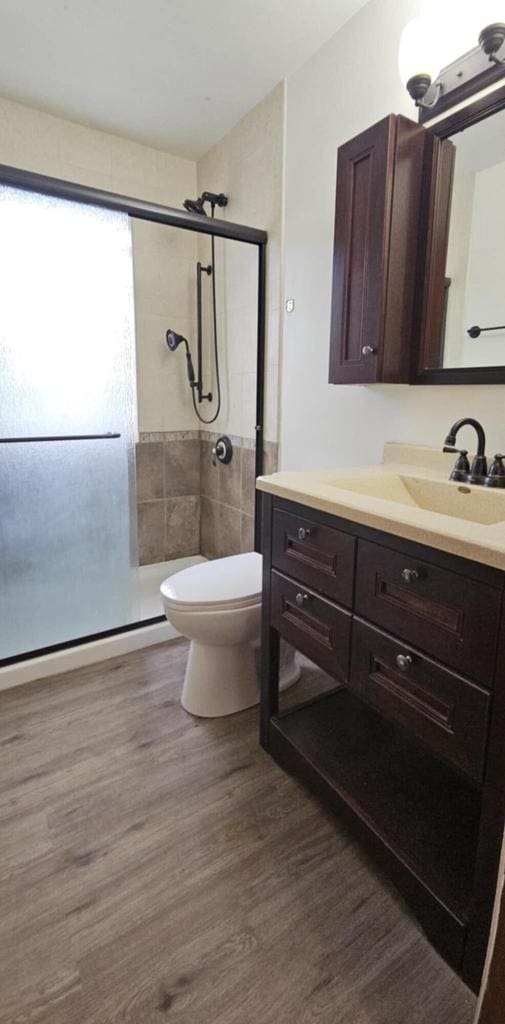 2210 Taylor Ave, Racine, WI 53403 - bathroom featuring a stall shower, vanity, wood finished floors, and toilet