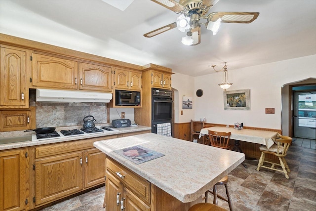 W7211 Pine Rd, Thorp, WI 54771 - kitchen featuring under cabinet range hood, black appliances, stone finish flooring, arched walkways, and backsplash