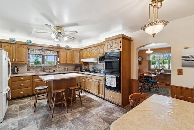 W7211 Pine Rd, Thorp, WI 54771 - kitchen with a sink, arched walkways, under cabinet range hood, brown cabinets, and light countertops
