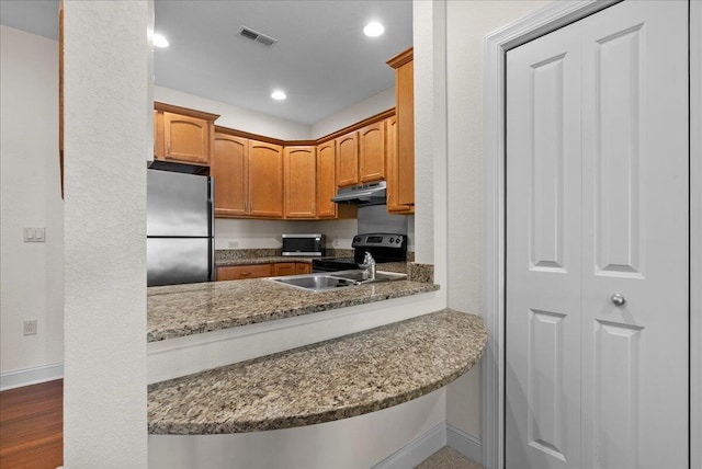 832 N 6th St Unit 118, Sheboygan, WI 53081 - kitchen featuring appliances with stainless steel finishes, under cabinet range hood, a sink, baseboards, and stone countertops