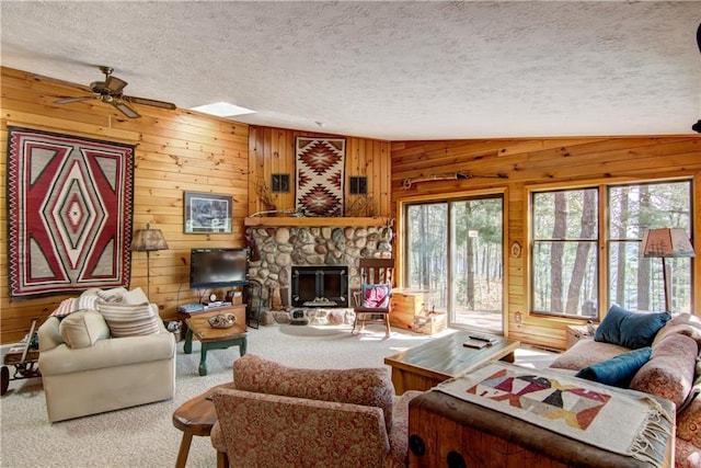 8360 W Shore Ln, Hayward, WI 54843 - living area with ceiling fan, wood walls, carpet floors, a textured ceiling, and a stone fireplace