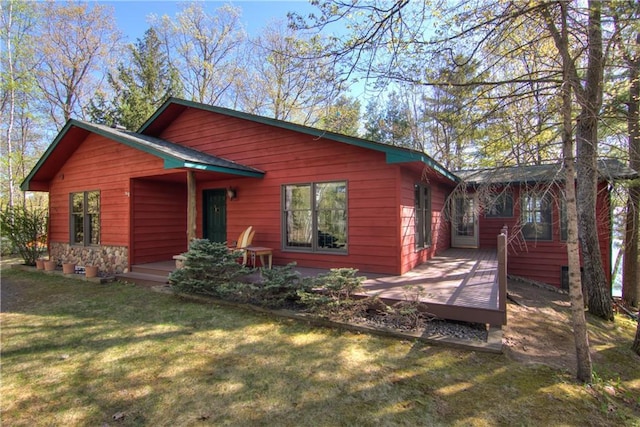 8360 W Shore Ln, Hayward, WI 54843 - view of front facade with a wooden deck, a front yard, and stone siding