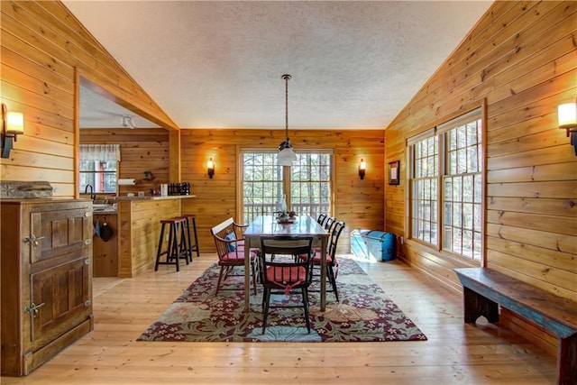 8360 W Shore Ln, Hayward, WI 54843 - dining area with vaulted ceiling, wooden walls, a textured ceiling, and light wood-style flooring