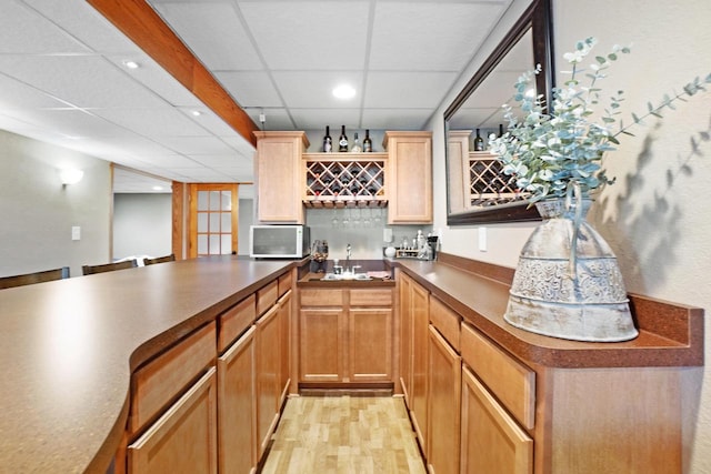 371 Thurow Dr, Oconomowoc, WI 53066 - kitchen featuring a sink, a drop ceiling, dark countertops, white microwave, and light wood-type flooring