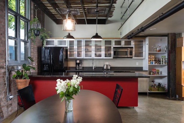 3059 N Weil St Unit 124, Milwaukee, WI 53212 - kitchen with black fridge with ice dispenser, stainless steel microwave, dark countertops, hanging light fixtures, and glass insert cabinets