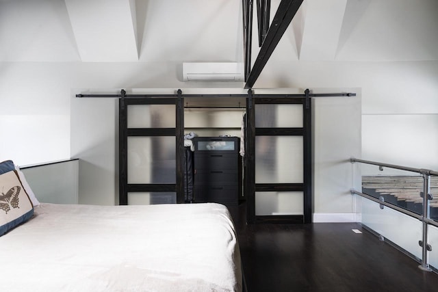 3059 N Weil St Unit 124, Milwaukee, WI 53212 - bedroom featuring a barn door, a wall unit AC, wood finished floors, and baseboards