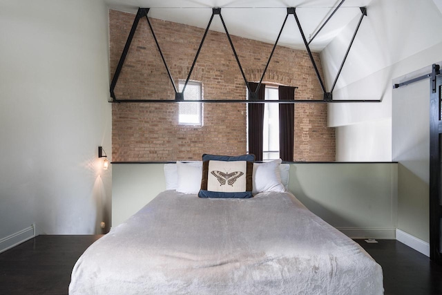 3059 N Weil St Unit 124, Milwaukee, WI 53212 - bedroom with brick wall, baseboards, wood finished floors, a high ceiling, and a barn door