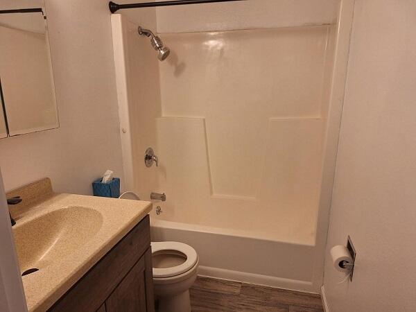 810 Railroad Ave, Viroqua, WI 54665 - bathroom featuring vanity, toilet, washtub / shower combination, and wood finished floors