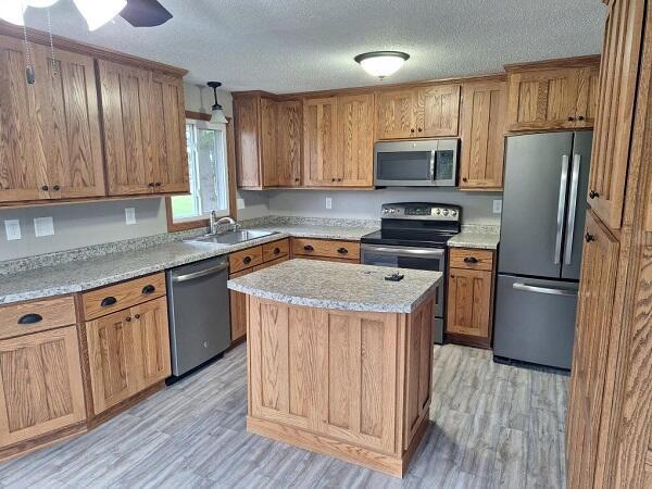 810 Railroad Ave, Viroqua, WI 54665 - kitchen with stainless steel appliances, a sink, light wood-style floors, a center island, and a textured ceiling