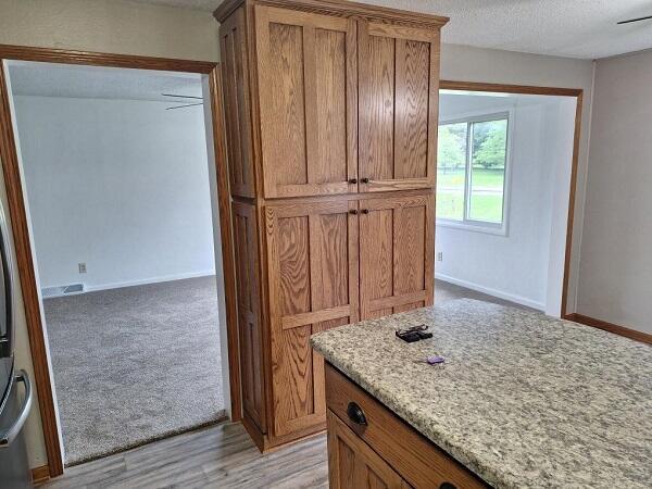 810 Railroad Ave, Viroqua, WI 54665 - kitchen with brown cabinetry, a textured ceiling, light stone counters, and baseboards