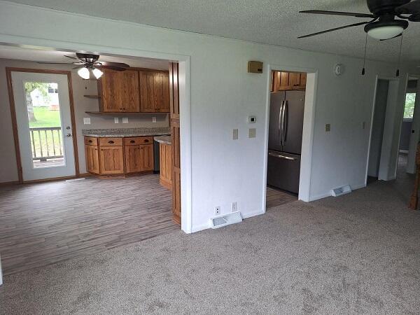 810 Railroad Ave, Viroqua, WI 54665 - kitchen featuring freestanding refrigerator, a ceiling fan, brown cabinetry, light colored carpet, and a textured ceiling