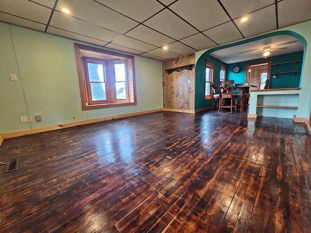 5183 2nd Ave, Pittsville, WI 54466 - unfurnished living room featuring arched walkways, hardwood / wood-style flooring, baseboards, a paneled ceiling, and ceiling fan