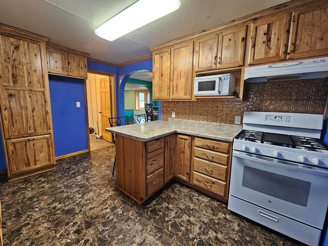 5183 2nd Ave, Pittsville, WI 54466 - kitchen with white appliances, under cabinet range hood, arched walkways, a peninsula, and light countertops